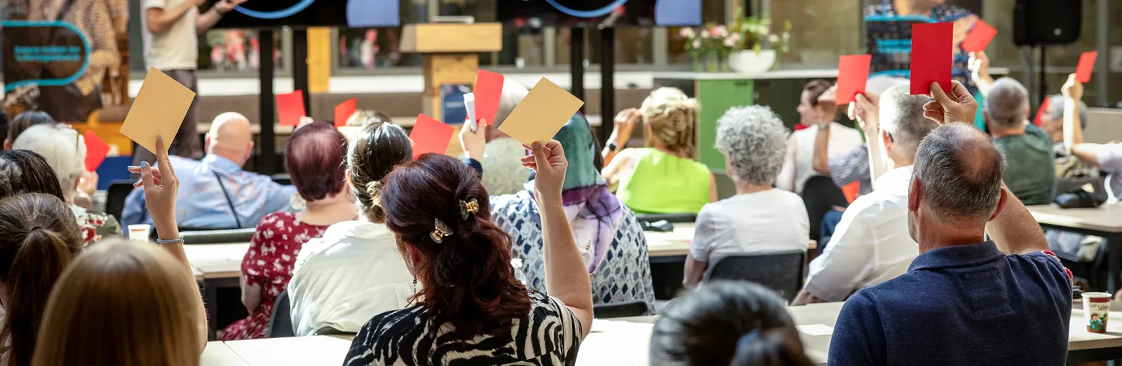 Groep mensen die kaartjes omhoog houden bij een stemming